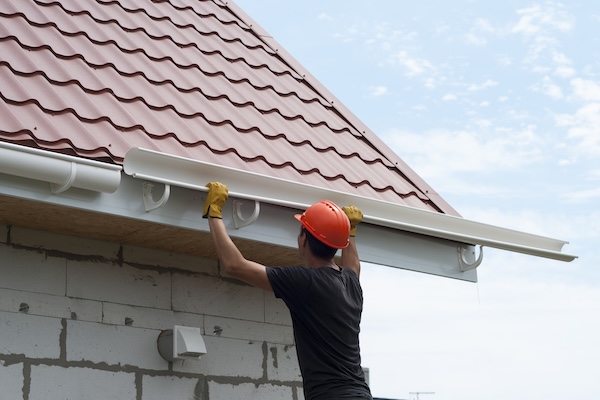Worker Installs The Gutter System On The Roof